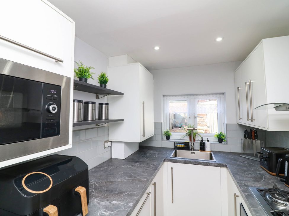 A kitchen with a microwave, sink and plants at 11 Regent Street in Melton Mowbray