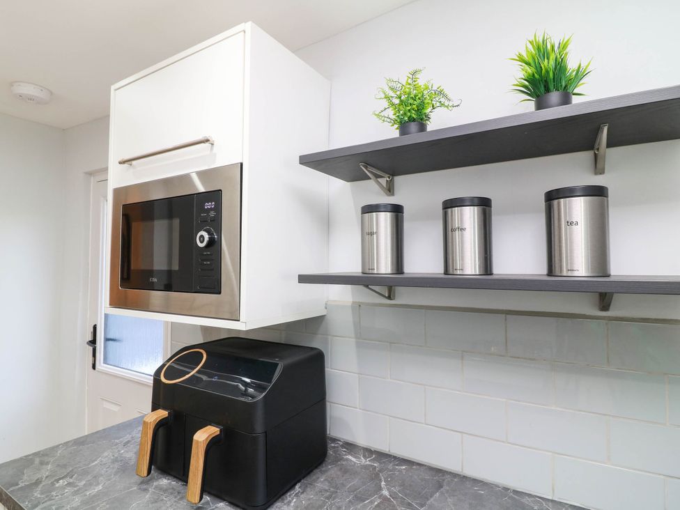 A kitchen with a microwave and storage containers at 11 Regent Street Melton Mowbray