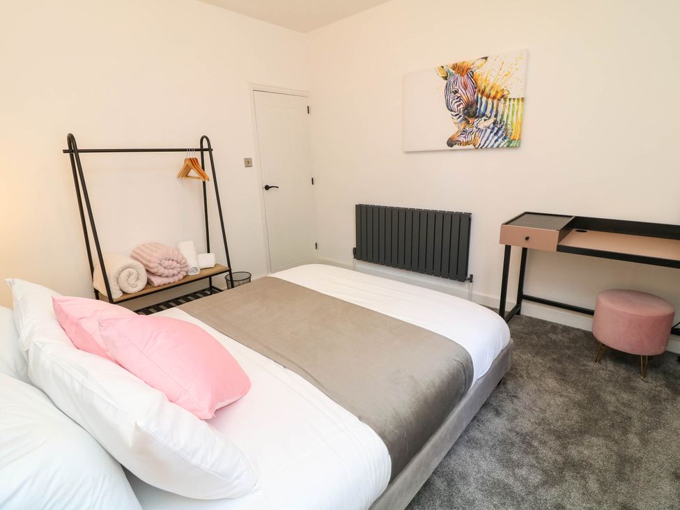A bedroom with a bed, desk, and artwork at 11 Regent Street in Melton Mowbray
