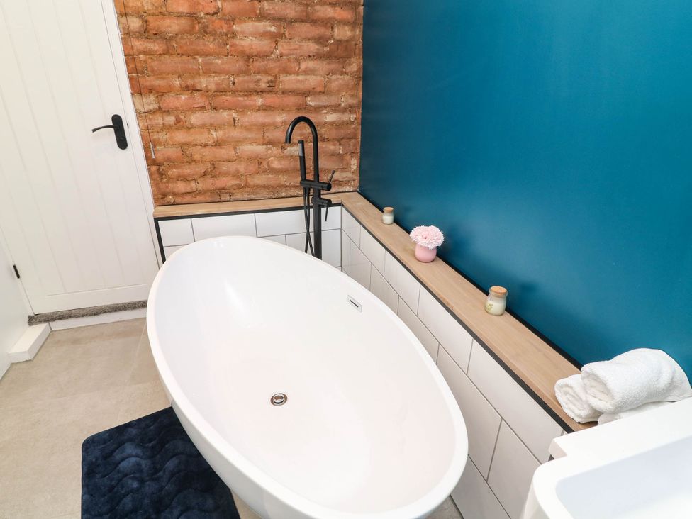 A bathroom with a bathtub and shelf at 11 Regent Street in Melton Mowbray