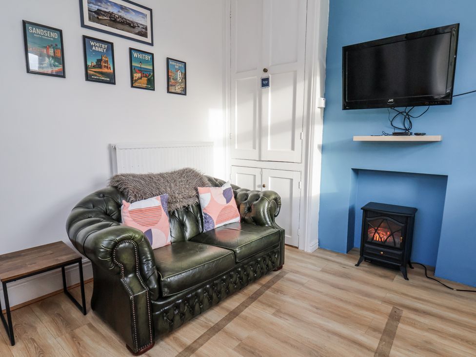 A living room with a green sofa and television at Hornblower Lodge in Whitby