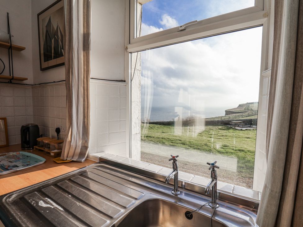 A kitchen with a sink and view of the sea at Hornblower Lodge in Whitby