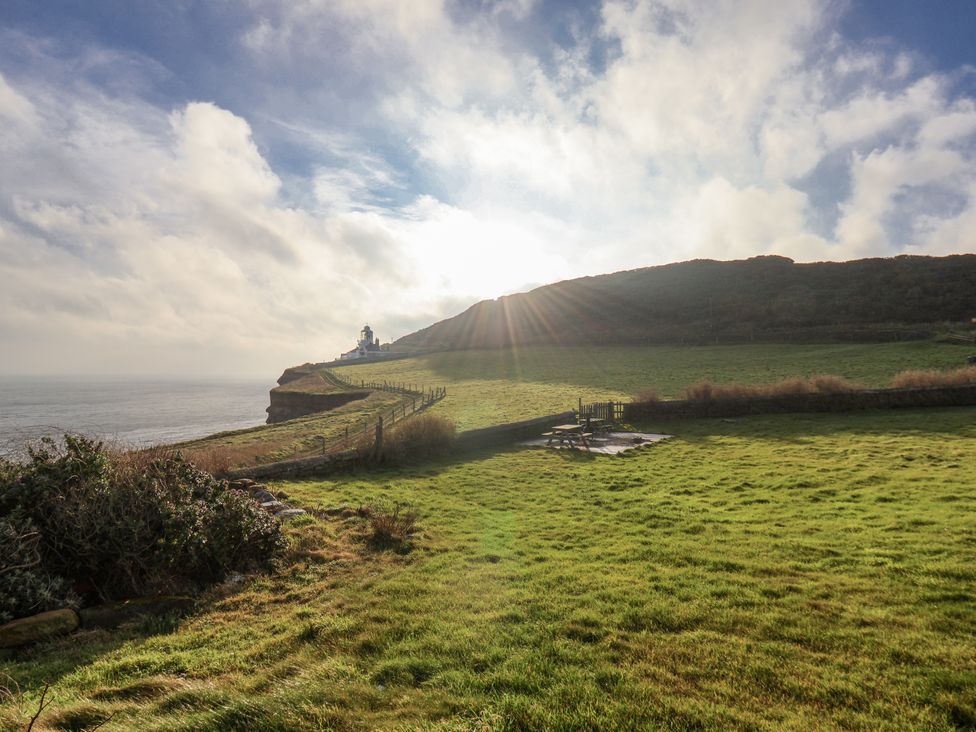 A cliff overlooking the ocean with a lighthouse at Hornblower Lodge in Whitby