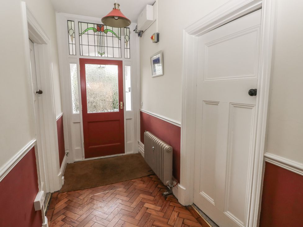 A hallway with a red door and wooden flooring at Kenvor in Newport, Pembrokeshire