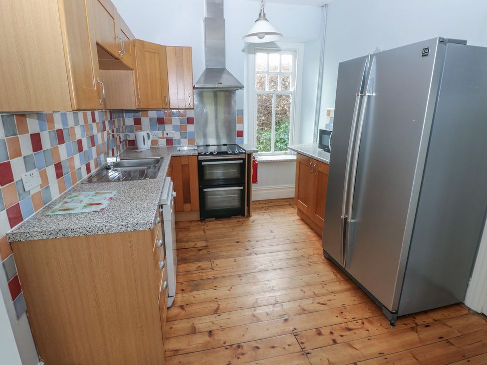 A kitchen with cabinets, oven, sink, and refrigerator at Kenvor in Newport, Pembrokeshire