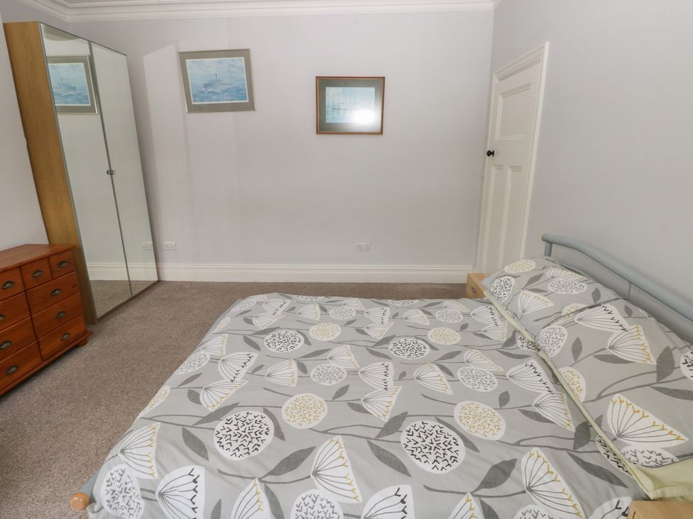 A bedroom with a bed and a mirror at Kenvor in Newport, Pembrokeshire
