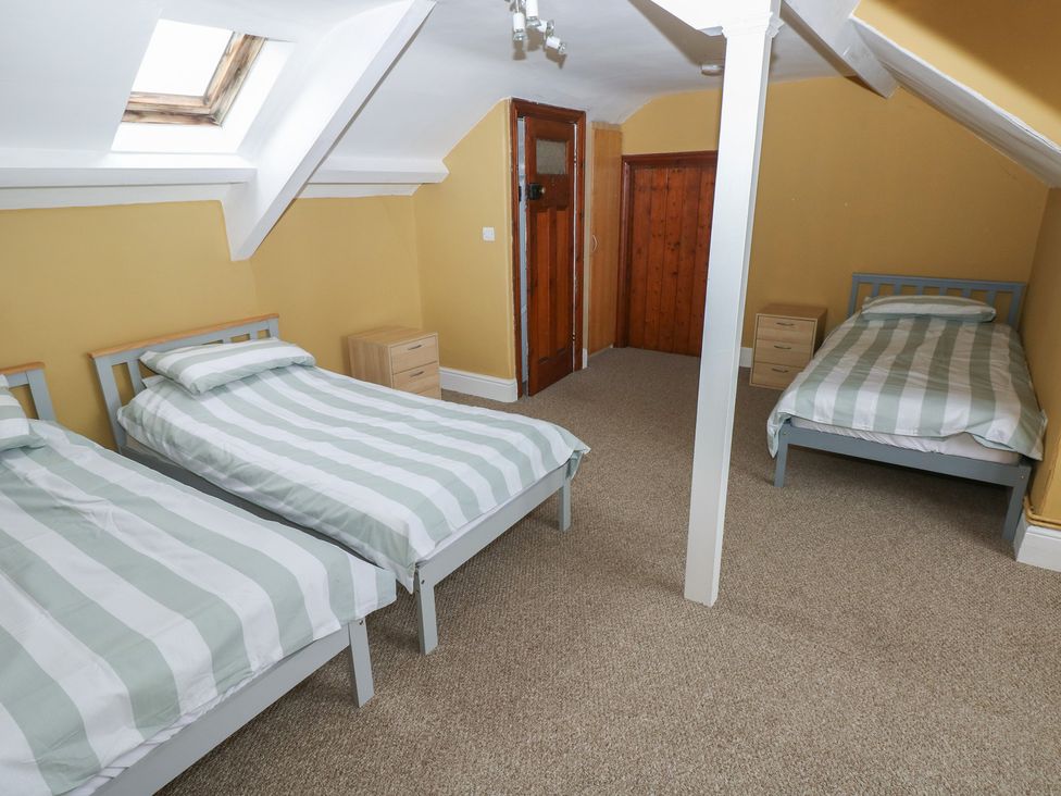 A bedroom with three beds and a door at Kenvor Newport, Pembrokeshire