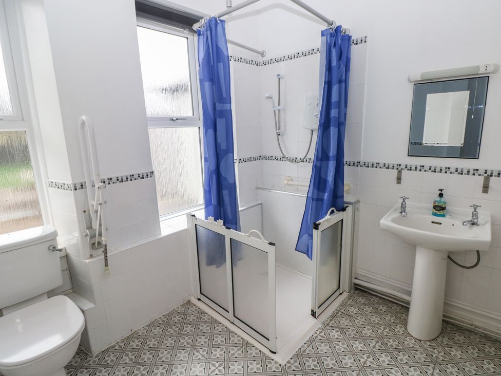A bathroom featuring a shower with curtain, sink and toilet at Kenvor, Newport, Pembrokeshire