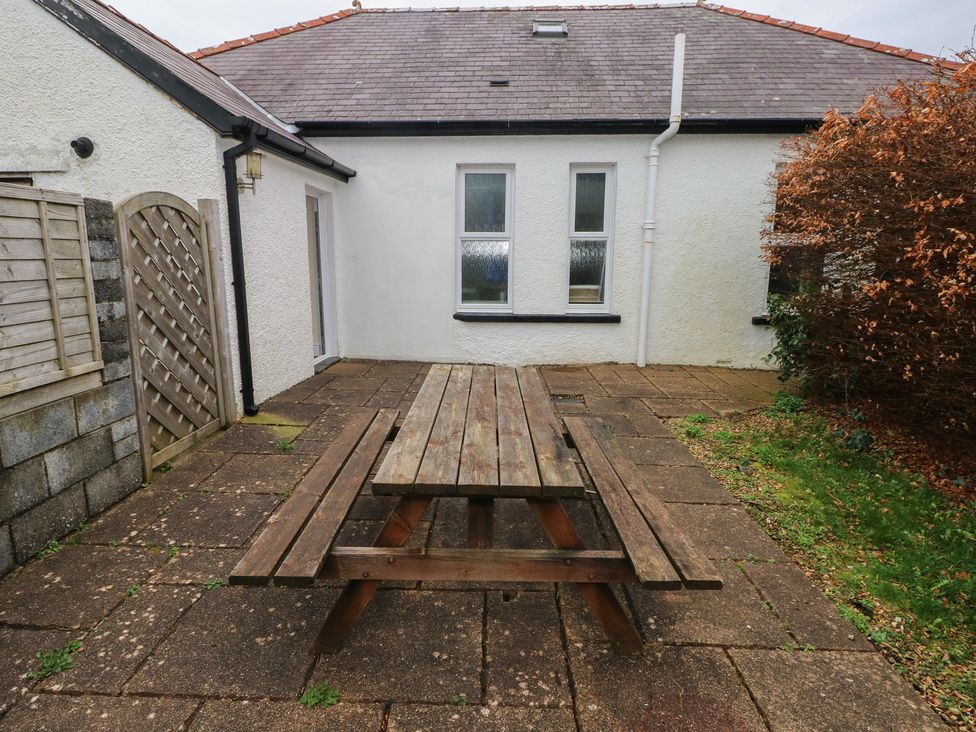 An outdoor area with a wooden table and surrounding walls at Kenvor, Newport, Pembrokeshire