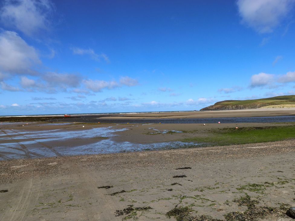 A beach with water and a boat at Kenvor in Newport, Pembrokeshire