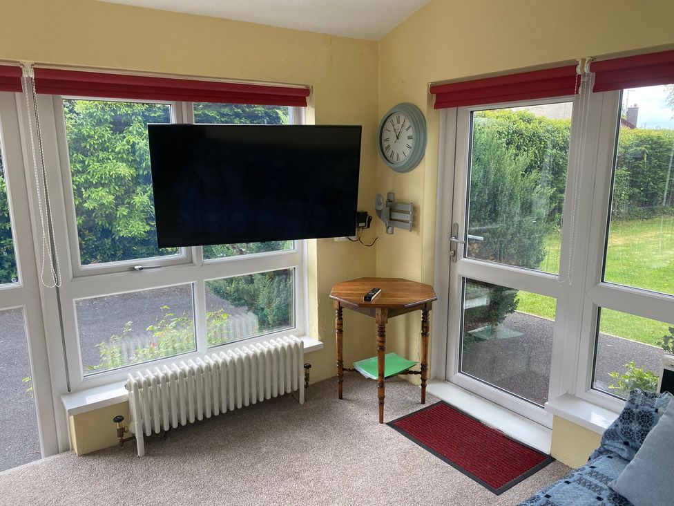 A conservatory with a television and table at Kenvor Newport, Pembrokeshire