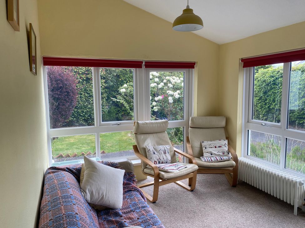 A sunroom with a sofa and armchairs at Kenvor in Newport, Pembrokeshire