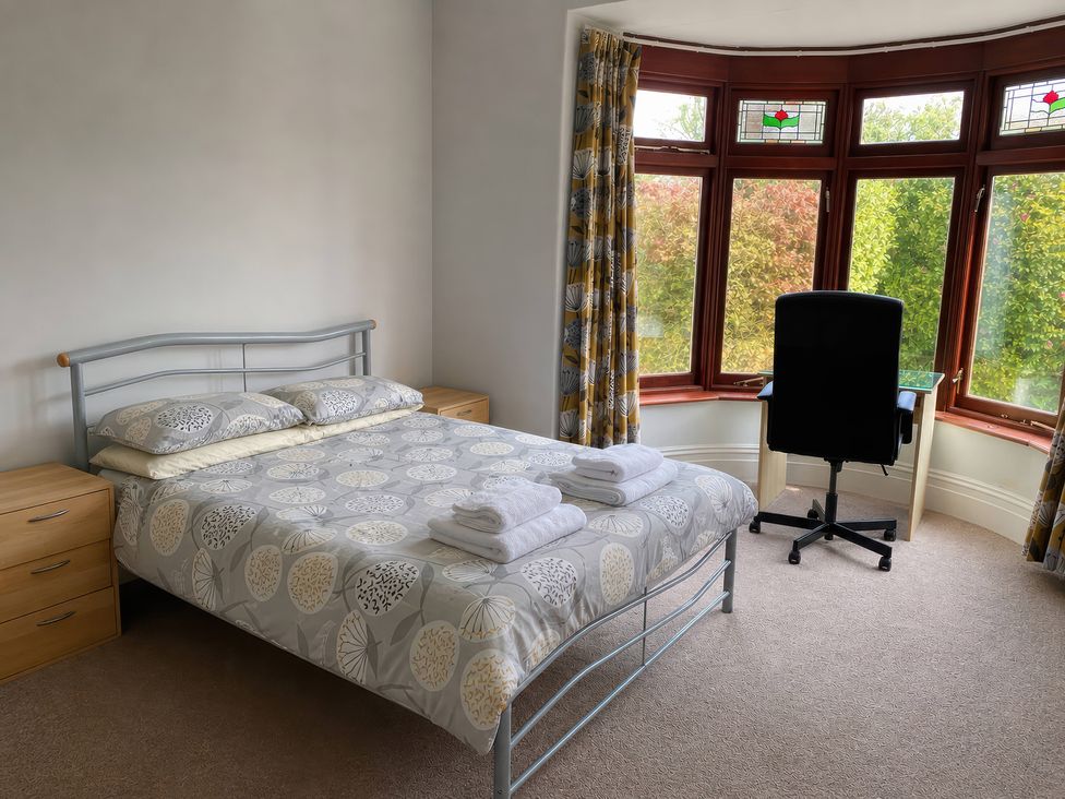 A bedroom with a bed and office chair at Kenvor in Newport, Pembrokeshire