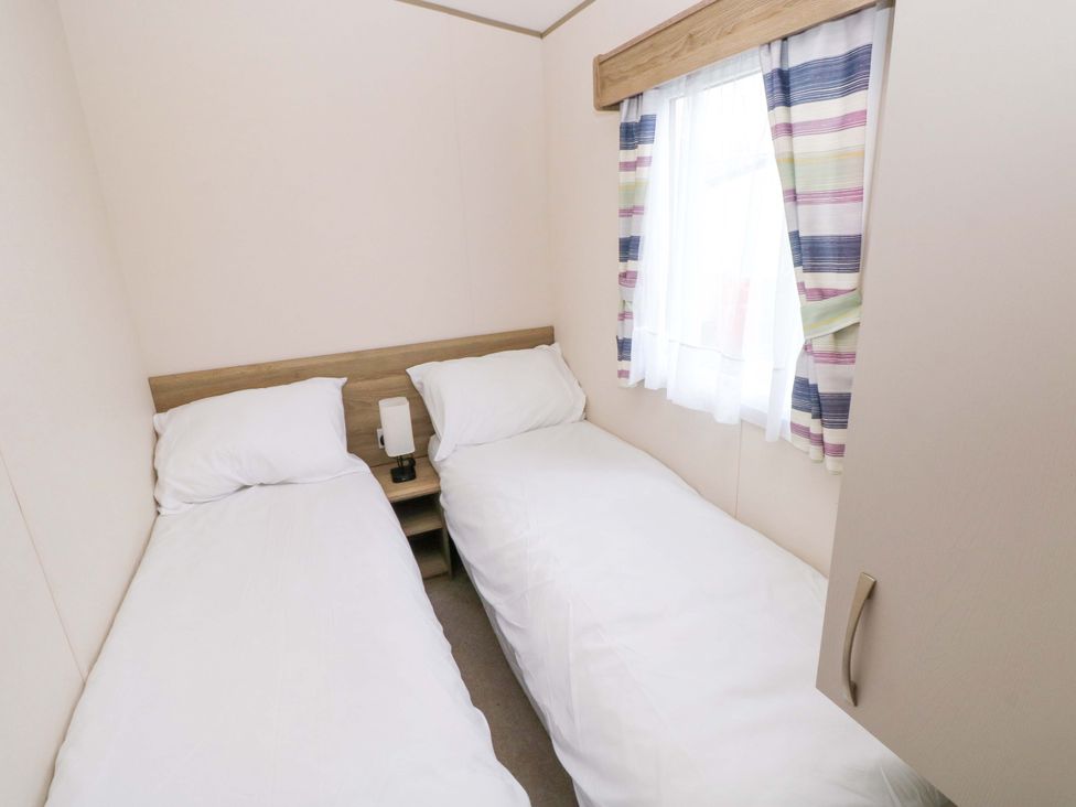 A bedroom with two single beds and a lamp at 82 Manorbier Park in Manorbier