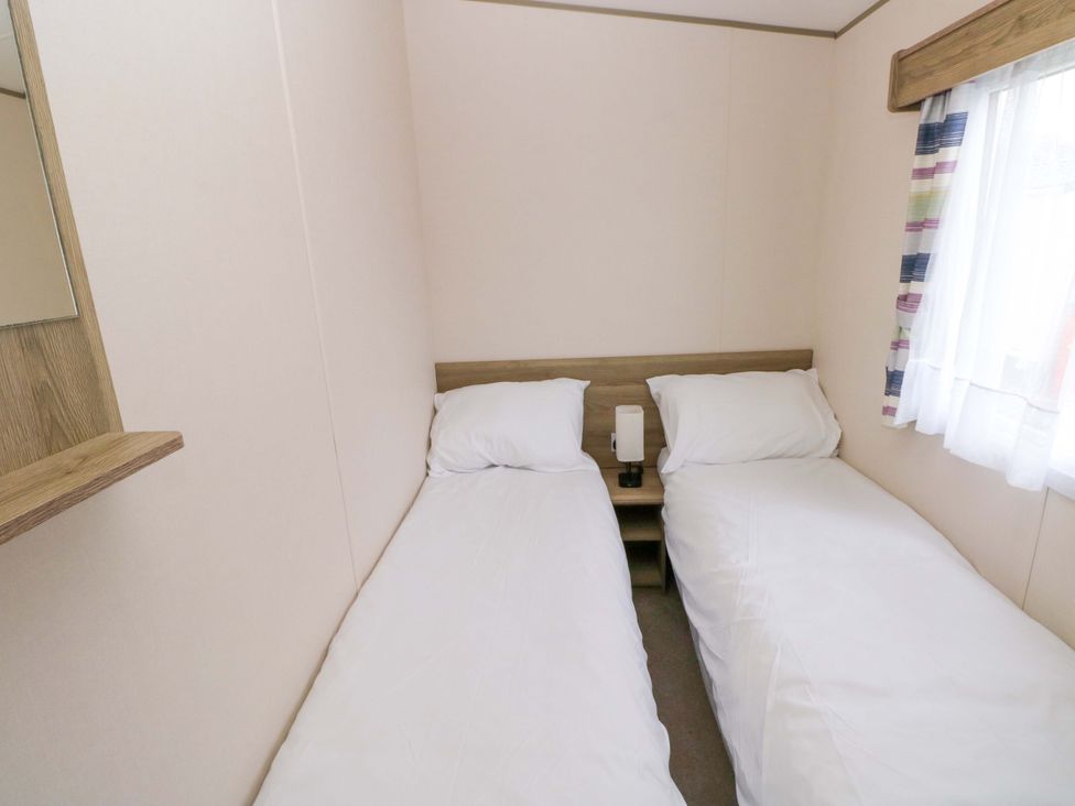 A bedroom with two single beds and a nightstand at 82 Manorbier Park in Manorbier