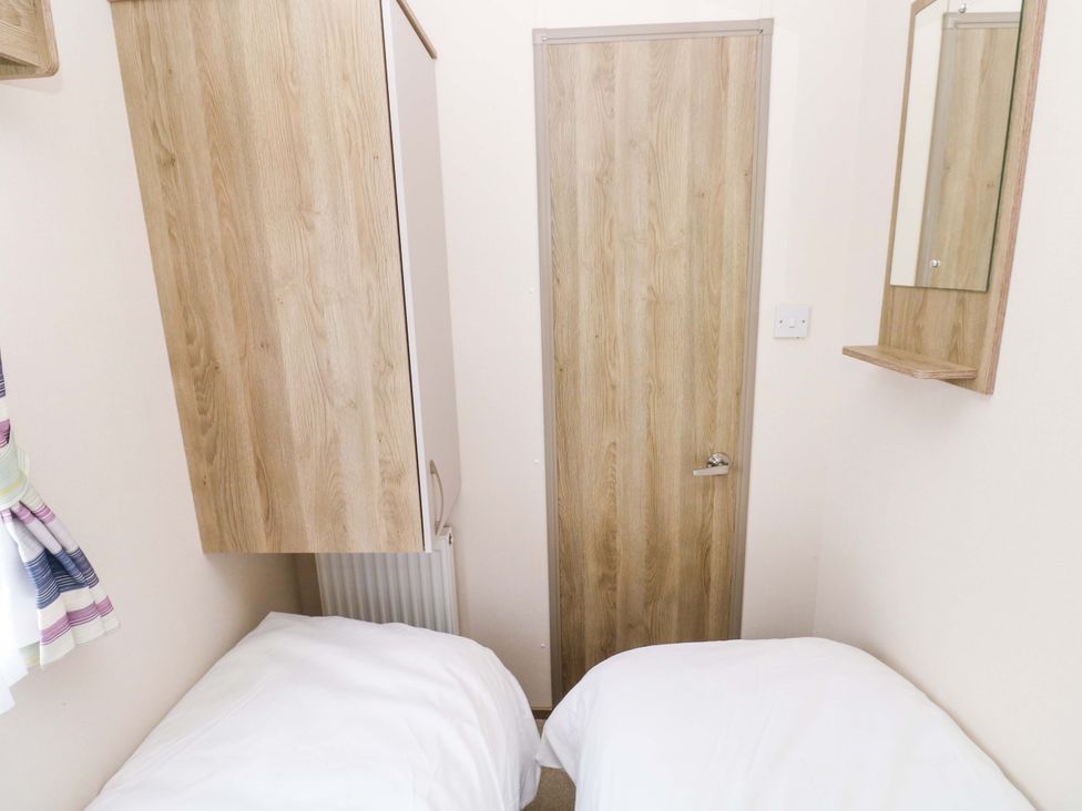 A bedroom with two single beds and storage at 82 Manorbier Park, Manorbier