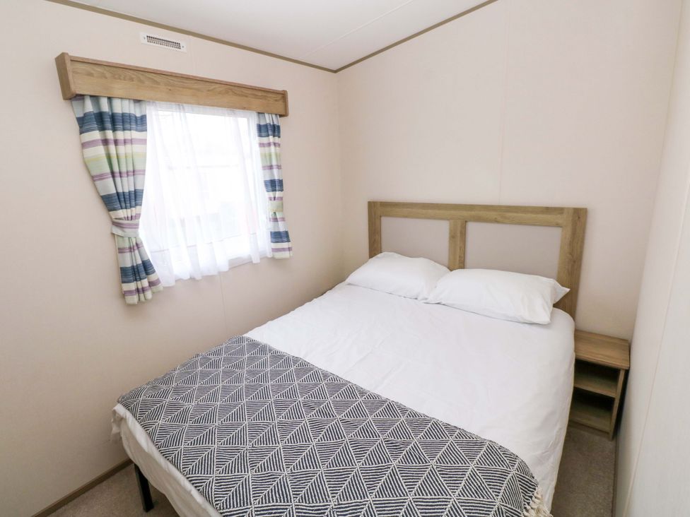 A bedroom with a double bed and window at 82 Manorbier Park, Manorbier