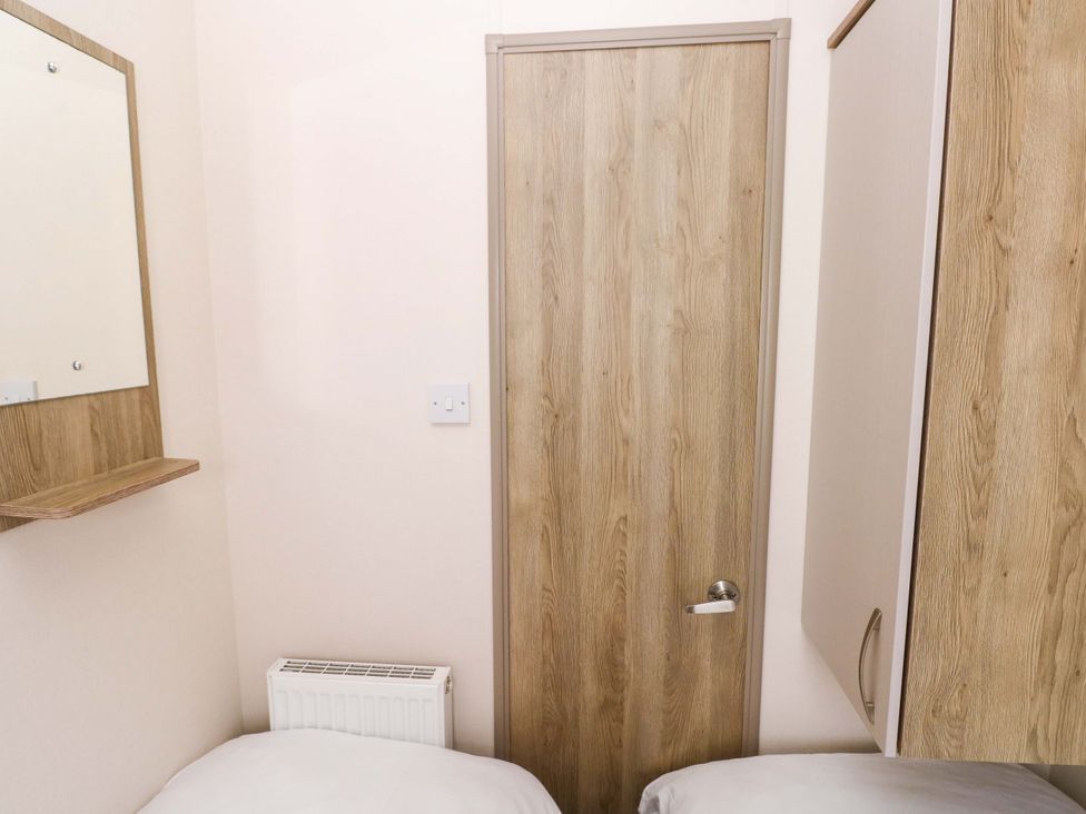 A bedroom with a mirror and door at 82 Manorbier Park in Manorbier