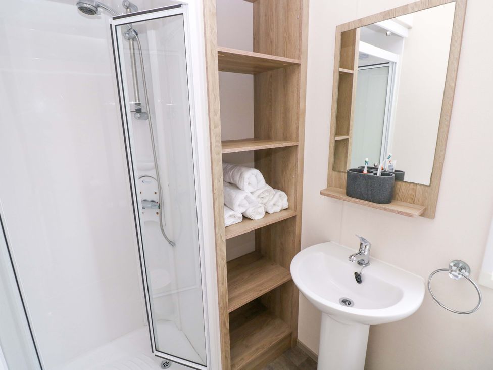 A bathroom with a shower, sink, and towels at 82 Manorbier Park in Manorbier