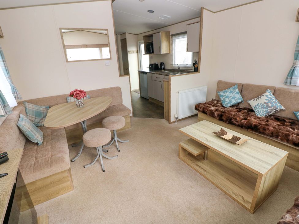 A living room with a dining table and sofa at 82 Manorbier Park in Manorbier