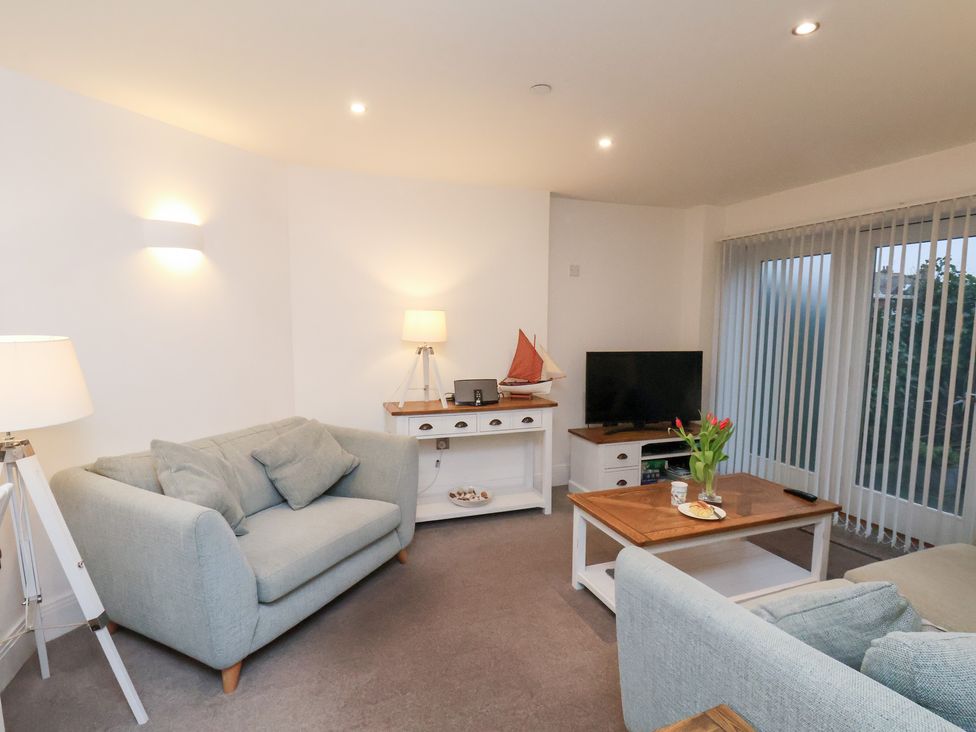 A living room with a sofa, lamp, and television at One Union Mill - garden apartment in Whitby
