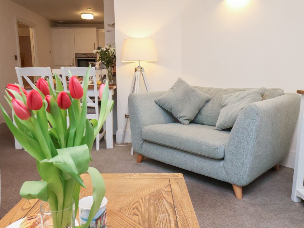 A living room with a sofa and flowers at One Union Mill - garden apartment in Whitby