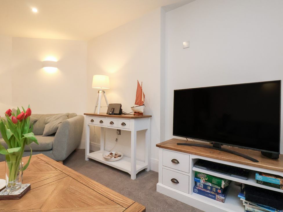 A living room with a sofa, television, and table at One Union Mill - garden apartment Whitby