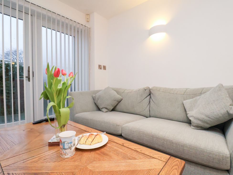 A living room with a sofa, flowers, and a table at One Union Mill - garden apartment in Whitby