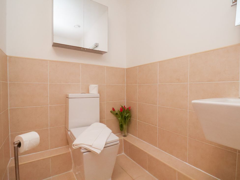 A bathroom with a toilet, mirror, and sink at One Union Mill - garden apartment in Whitby