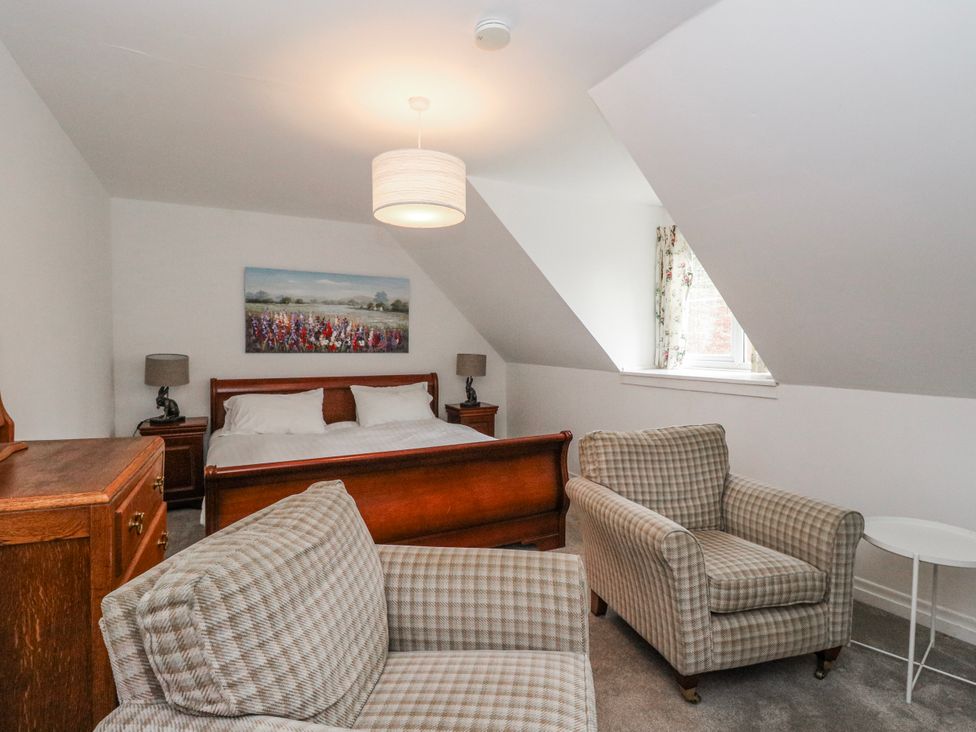 A bedroom with a bed and armchairs at Sycamore, Killean Farmhouse Cottages near Inveraray