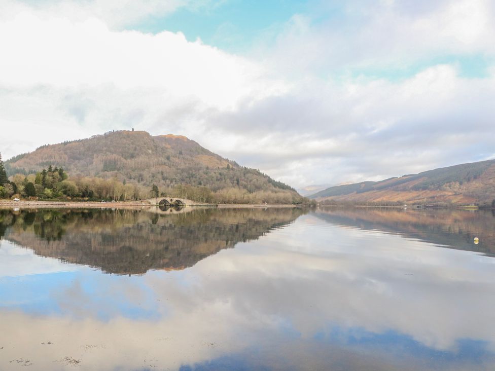 A lake with reflections of hills and trees at Sycamore near Killean Farmhouse Cottages near Inveraray