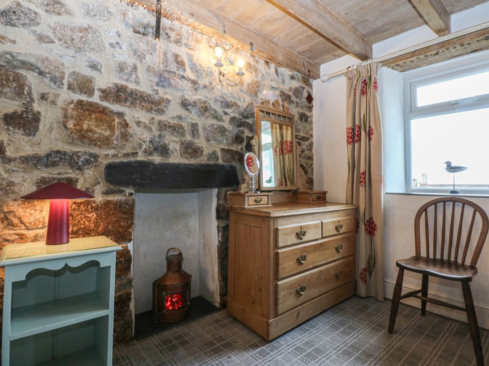 A bedroom with a wooden dresser and stone wall at Parc y Brenin Holidays, Abersoch