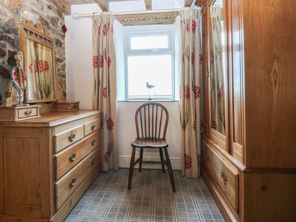 A bedroom with a wooden dresser, chair, and curtains at Parc y Brenin Holidays, Abersoch