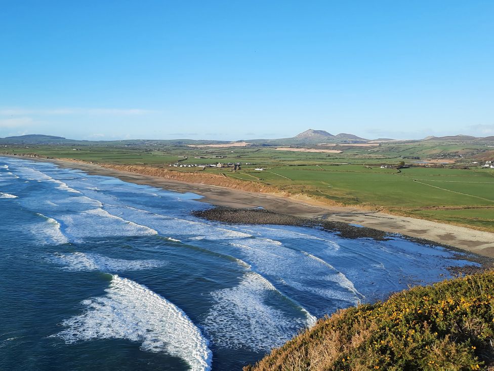A scenic view of ocean waves and beach with hills in the background at Parc y Brenin Holidays, Cilan near Abersoch