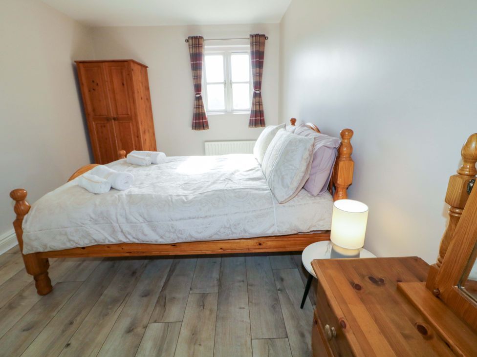 A bedroom with a bed, wardrobe, and lamp at Innishore Cottage in 
