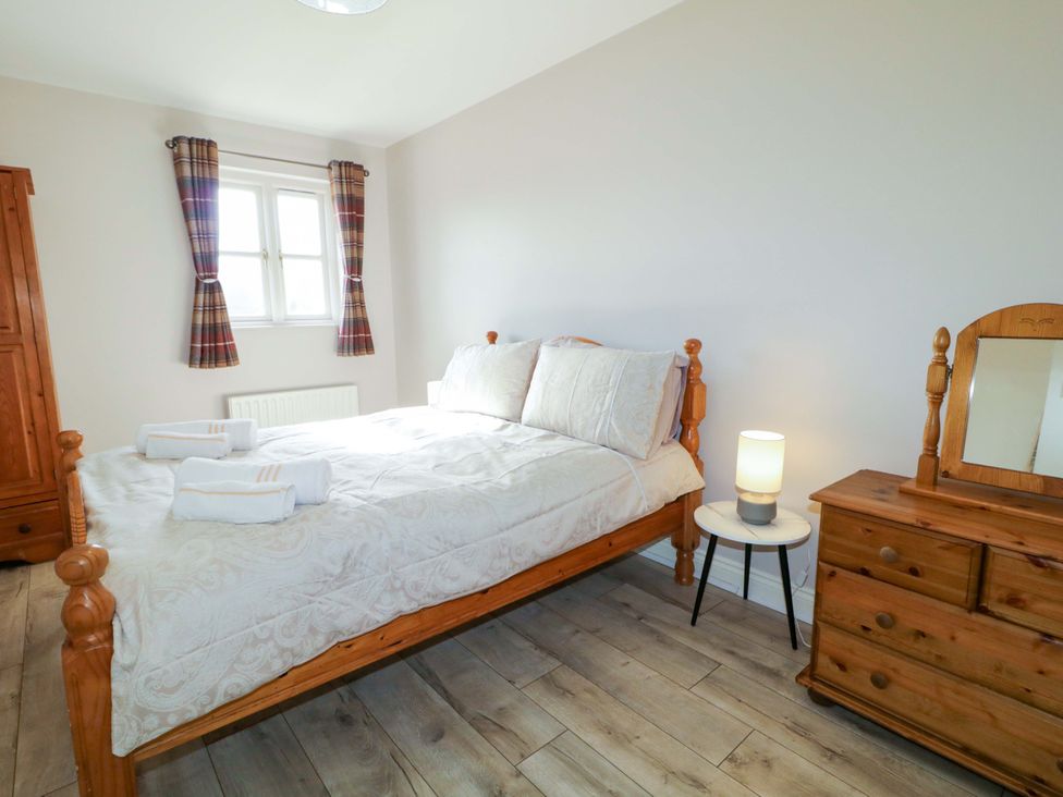 A bedroom with a bed and a wardrobe at Innishore Cottage