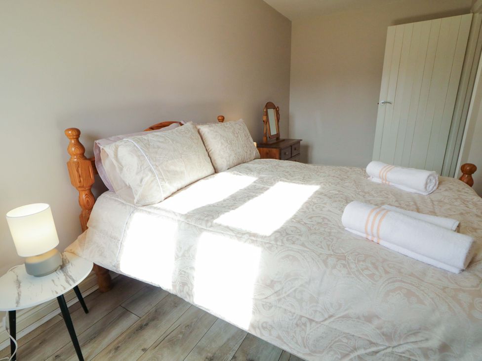 A bedroom with a bed and bedside table at Innishore Cottage