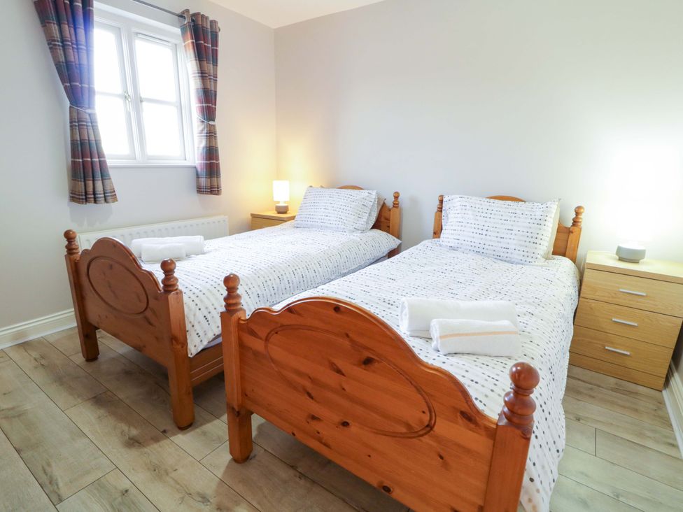 A bedroom with two single beds and a nightstand at Innishore Cottage