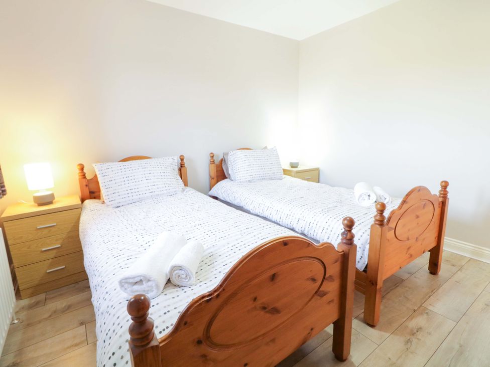 A bedroom with two single beds and a lamp at Innishore Cottage