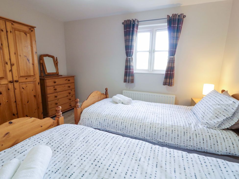 A bedroom with two beds and wooden furniture at Innishore Cottage