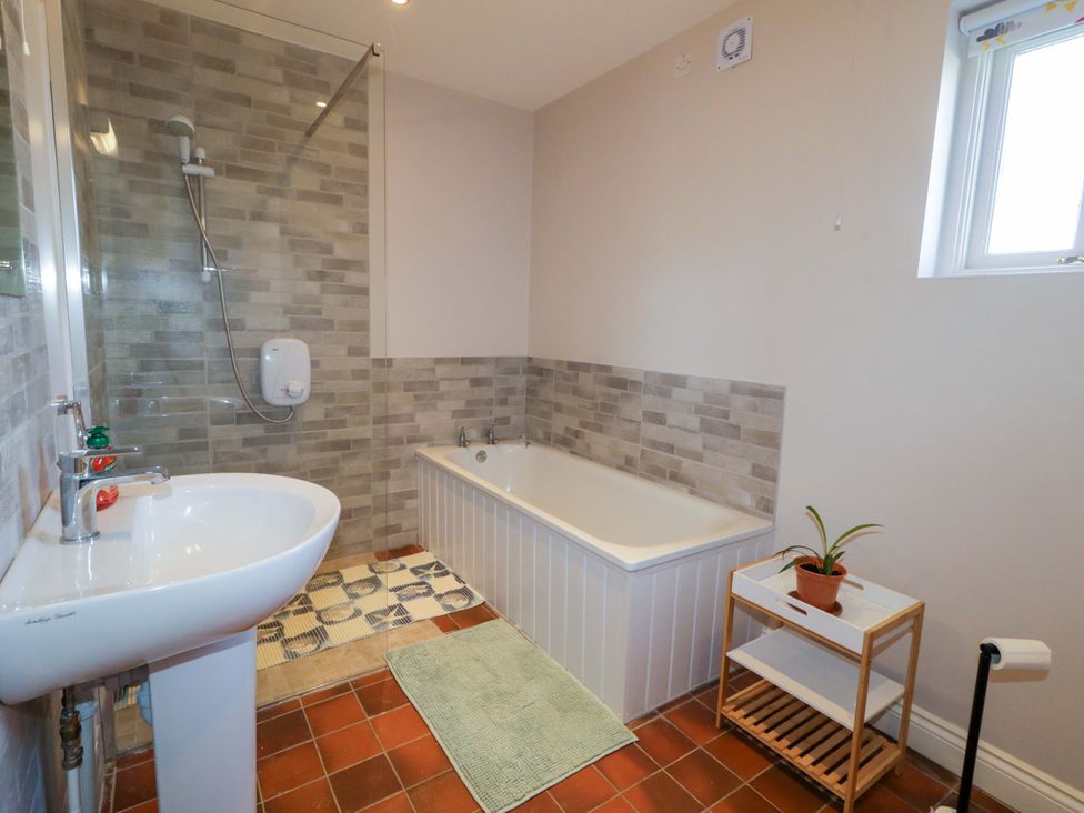 A bathroom with a shower and bathtub at Innishore Cottage