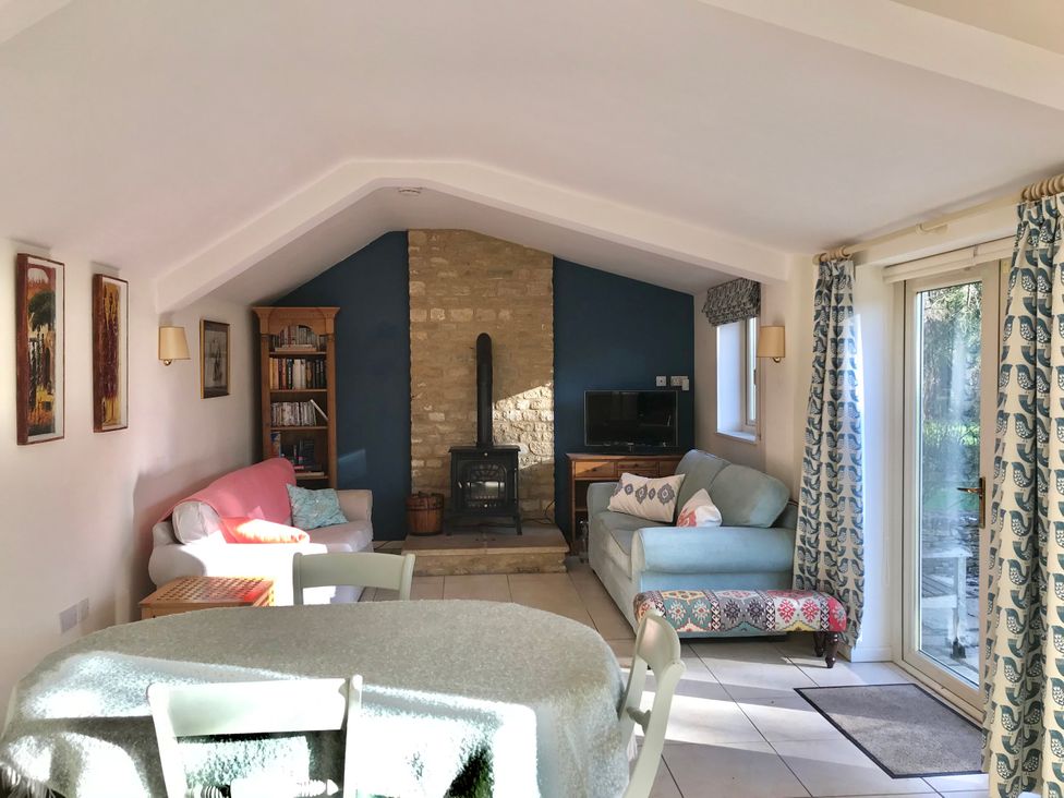 A living room with a fireplace and a bookshelf at Meadow Lodge in Cerney Wick near South Cerney, Cotswolds