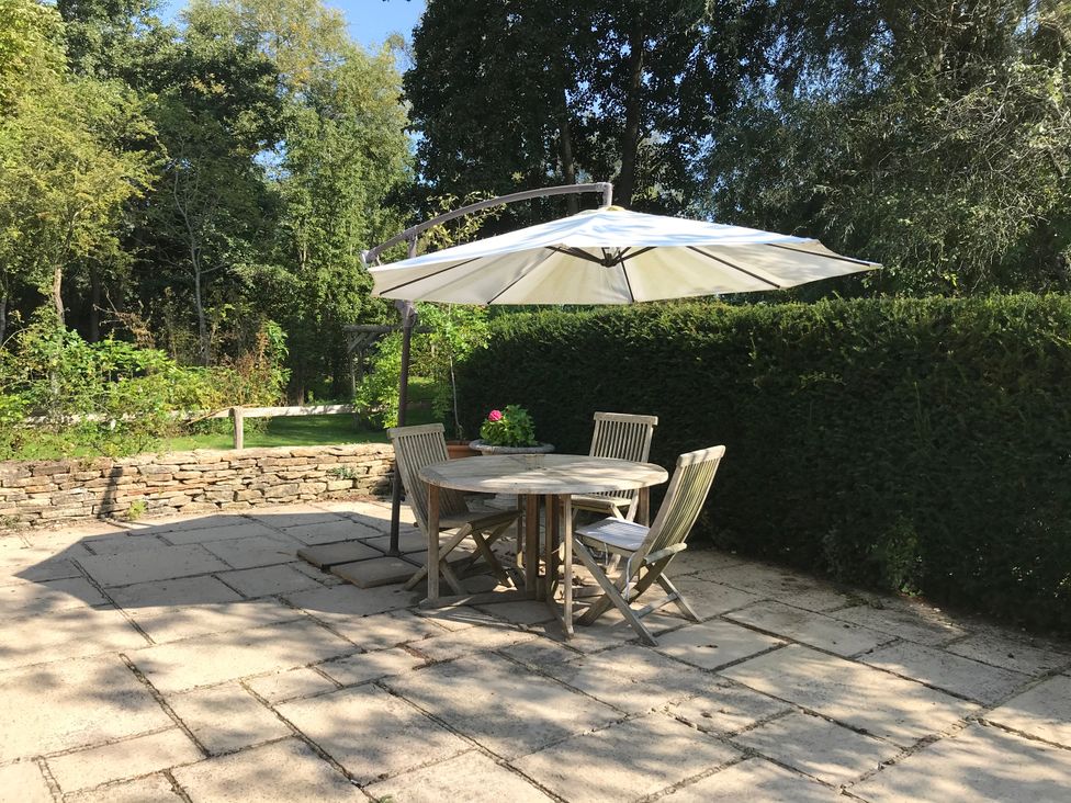 An outdoor seating area with a table and umbrellas at Meadow Lodge Cerney Wick near South Cerney Cotswolds