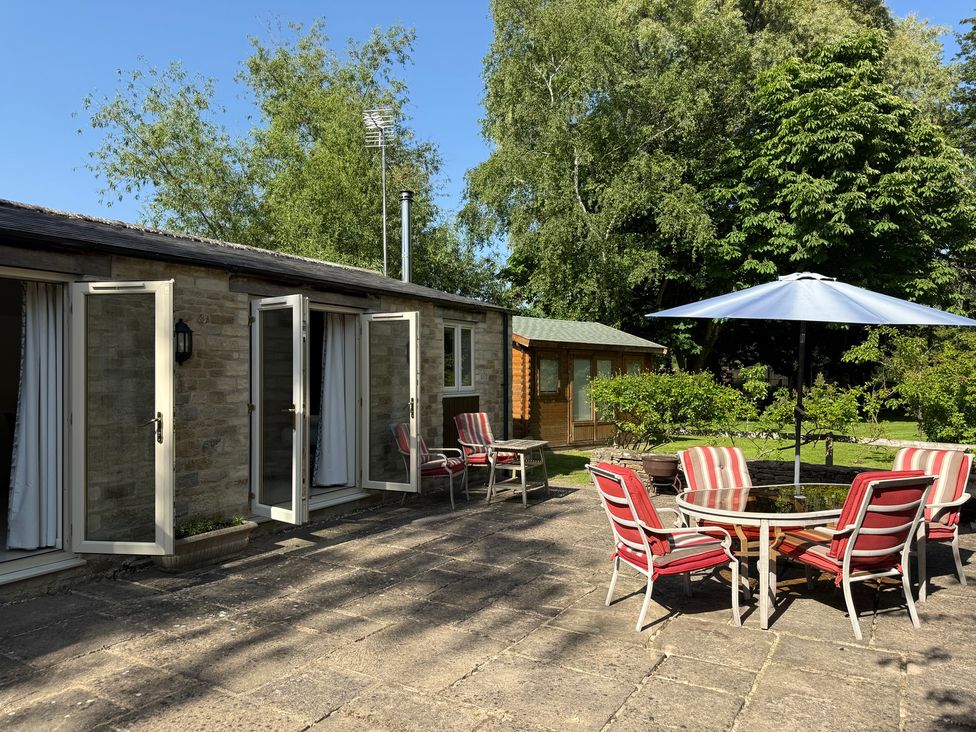 An outdoor seating area with chairs and a table at Meadow Lodge Cerney Wick near South Cerney Cotswolds