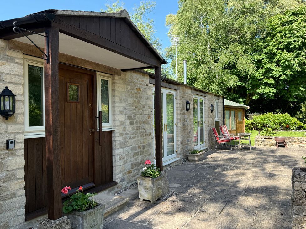An outdoor area with a doorway and flower pots at Meadow Lodge Cerney Wick near South Cerney, Cotswolds