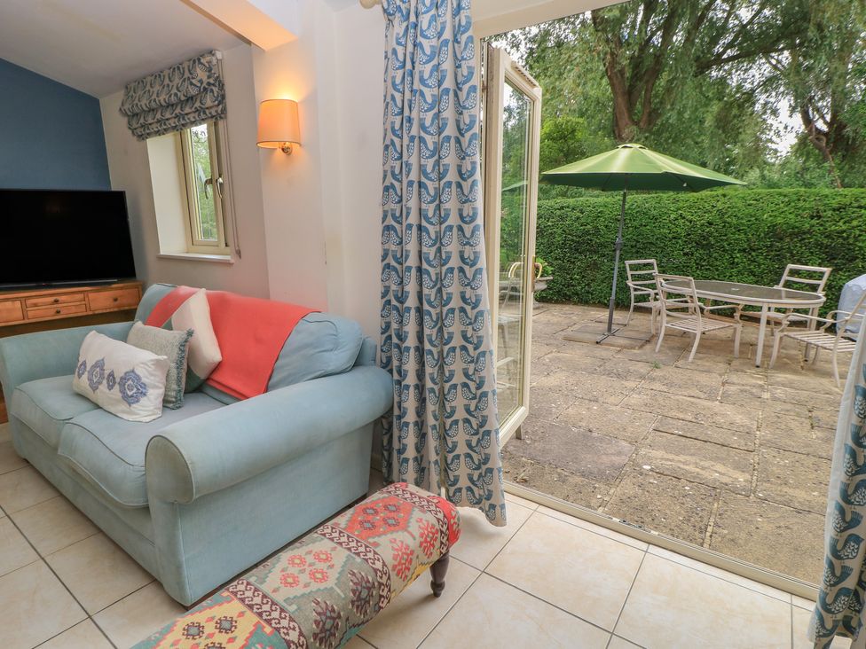 A living room with a sofa and television at Meadow Lodge in Cerney Wick near South Cerney, Cotswolds