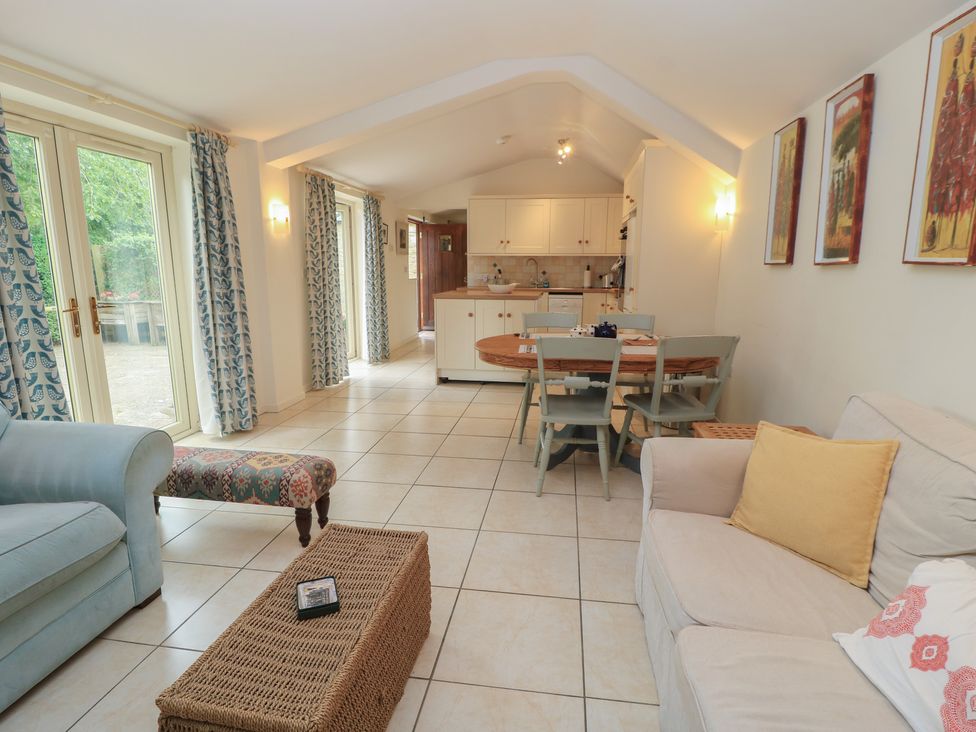 A living room with a sofa and dining area at Meadow Lodge in Cerney Wick near South Cerney, Cotswolds