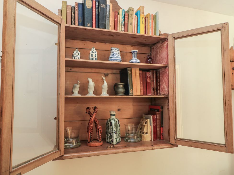 A wooden cabinet with books and decorative items at Meadow Lodge Cerney Wick near South Cerney, Cotswolds
