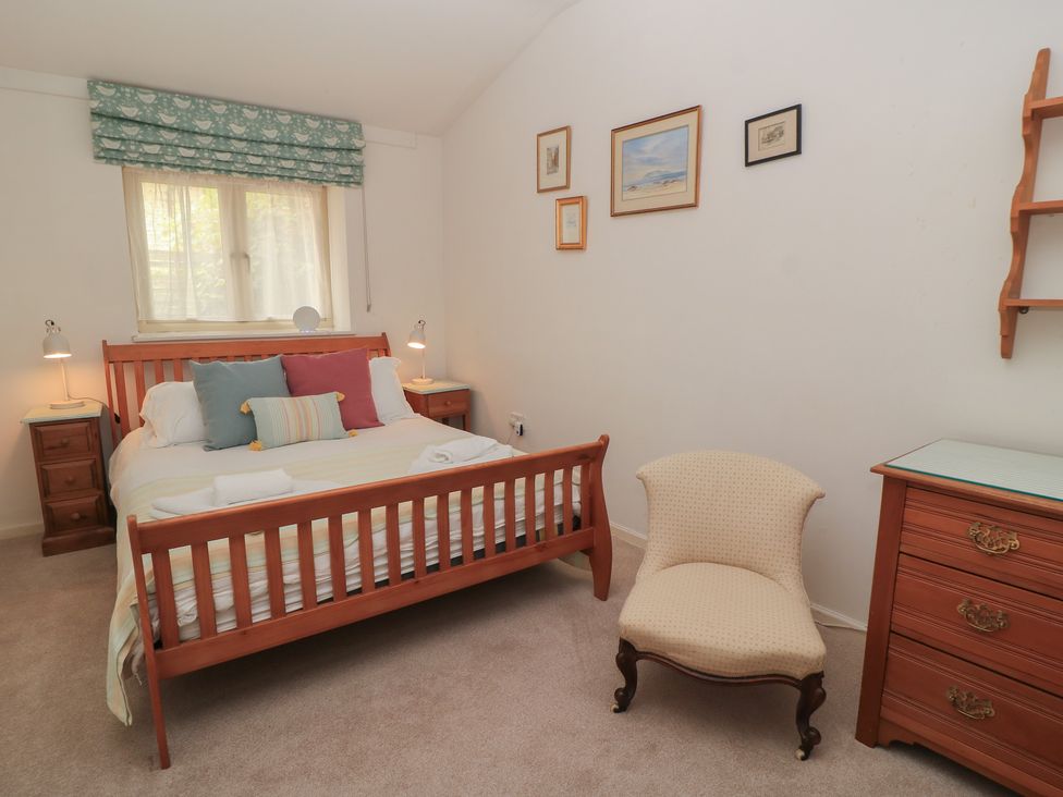 A bedroom with a bed, nightstands, lamps, and decorative frames at Meadow Lodge, Cerney Wick near South Cerney, Cotswolds