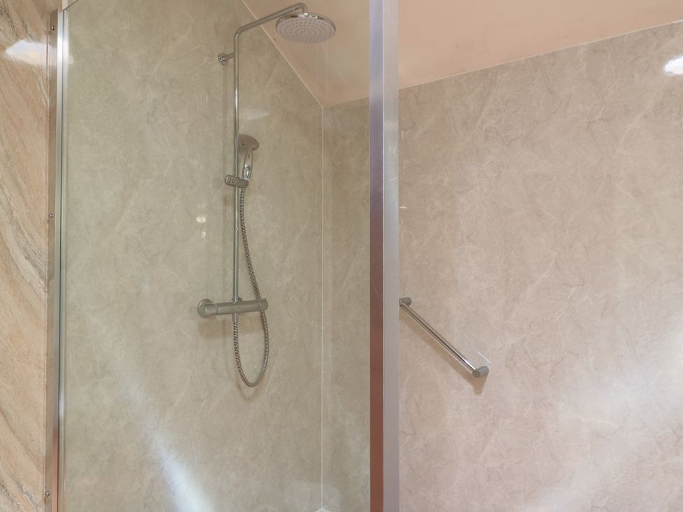 A shower with a showerhead and wall panel at Meadow Lodge Cerney Wick near South Cerney Cotswolds